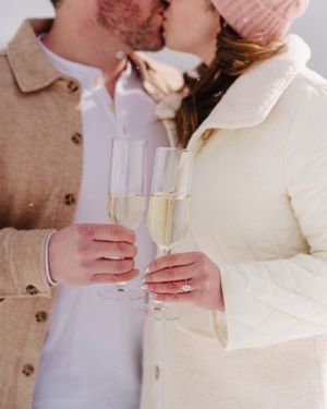 Romantic champagne toast with glasses against snowy mountain backdrop.