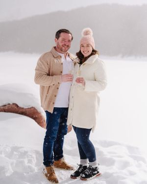 Happy winter engagement photo with couple in matching cream and tan coats.