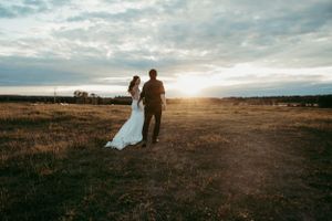 Silhouetted couple walks hand in hand during sunset on their wedding day.