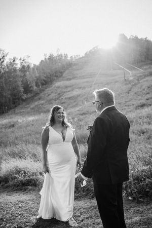 A couple shares a tender moment on a sunlit hillside during their wedding photoshoot.
