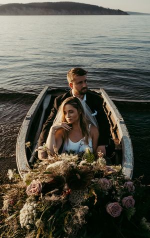 A romantic boat scene on a tranquil lake at sunset with floral decorations filling the wooden vessel's interior.