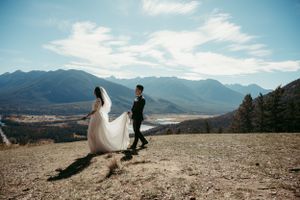 Wedding couple standing on mountain overlook with dramatic landscape views.