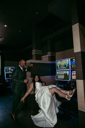 Four sequential photos show a couple in wedding attire having fun playing arcade games in a darkened entertainment venue.