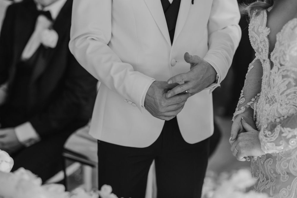 Detail shot of hands during wedding ceremony showing formal attire.