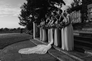 A black and white photo of bridesmaids lined up holding bouquets at an outdoor wedding venue.