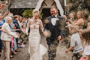 Joyous couple exiting church while guests shower them with confetti on their wedding day.
