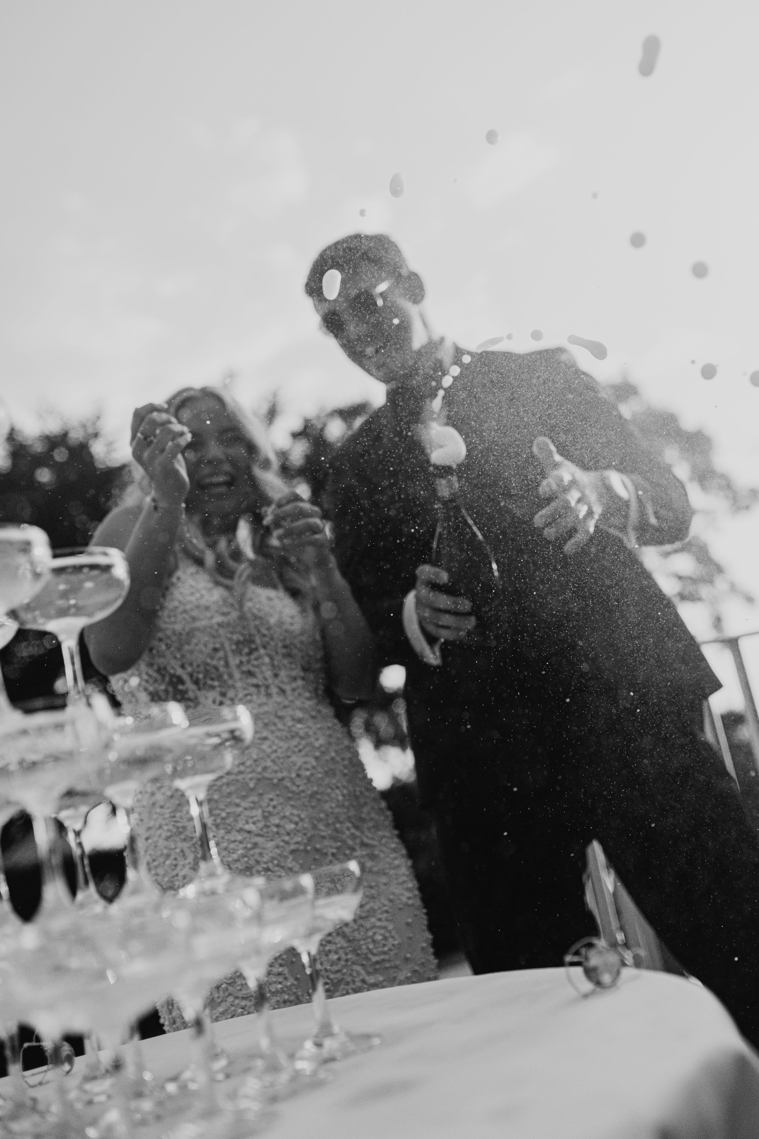 A vintage black and white photograph shows people gathered at a formal event with wine glasses and tables.