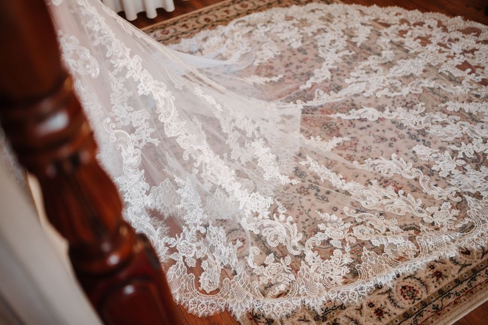 Close-up detail of intricate lace pattern on white wedding dress fabric.
