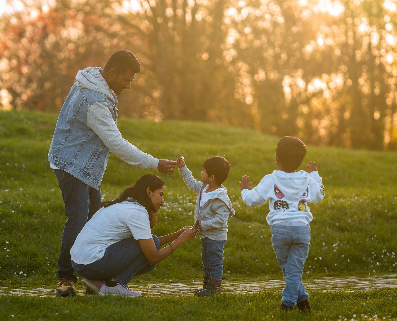 Family enjoying outdoor moment together at sunset in grassy field.