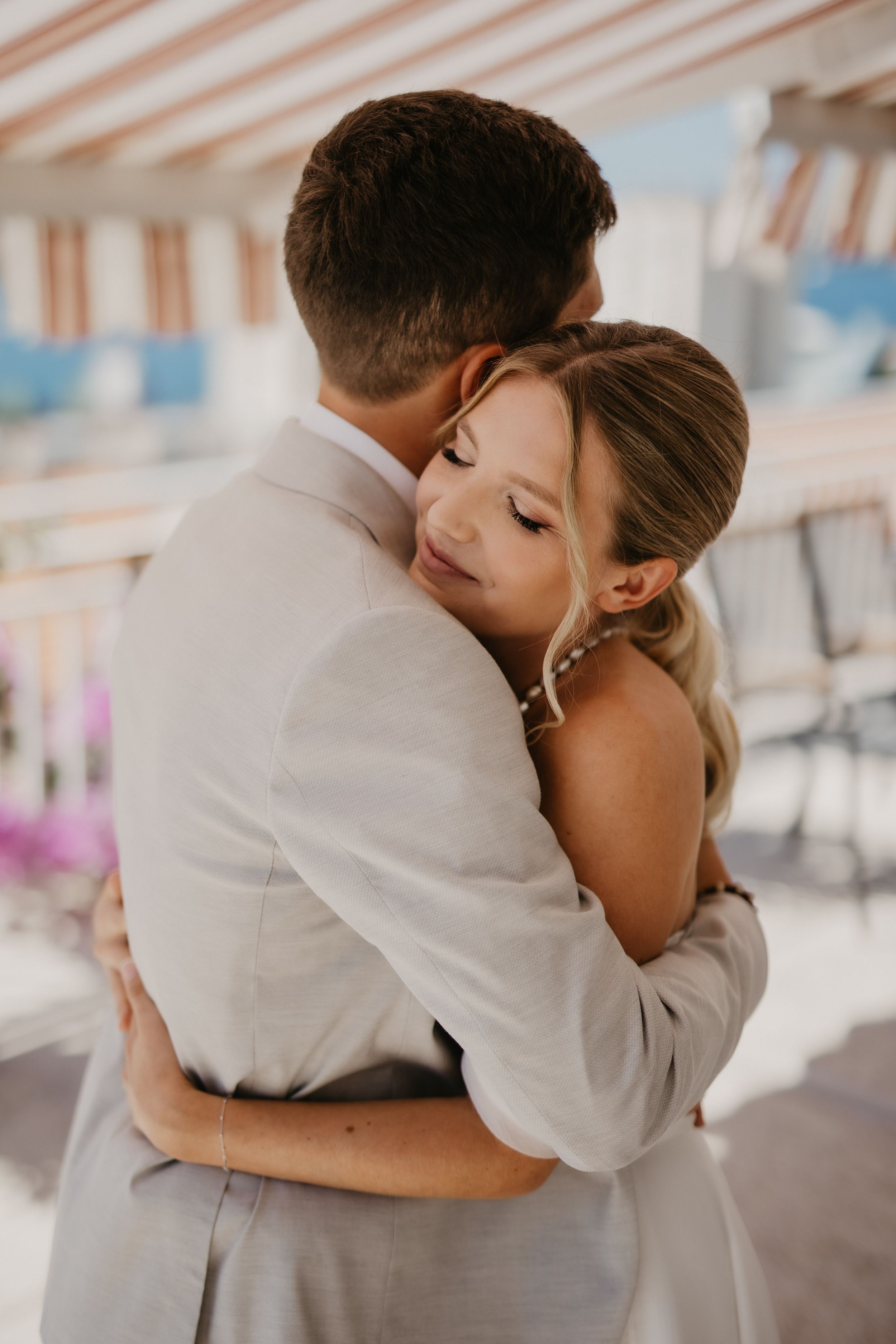 A tender moment between newlyweds as they embrace on a covered terrace.