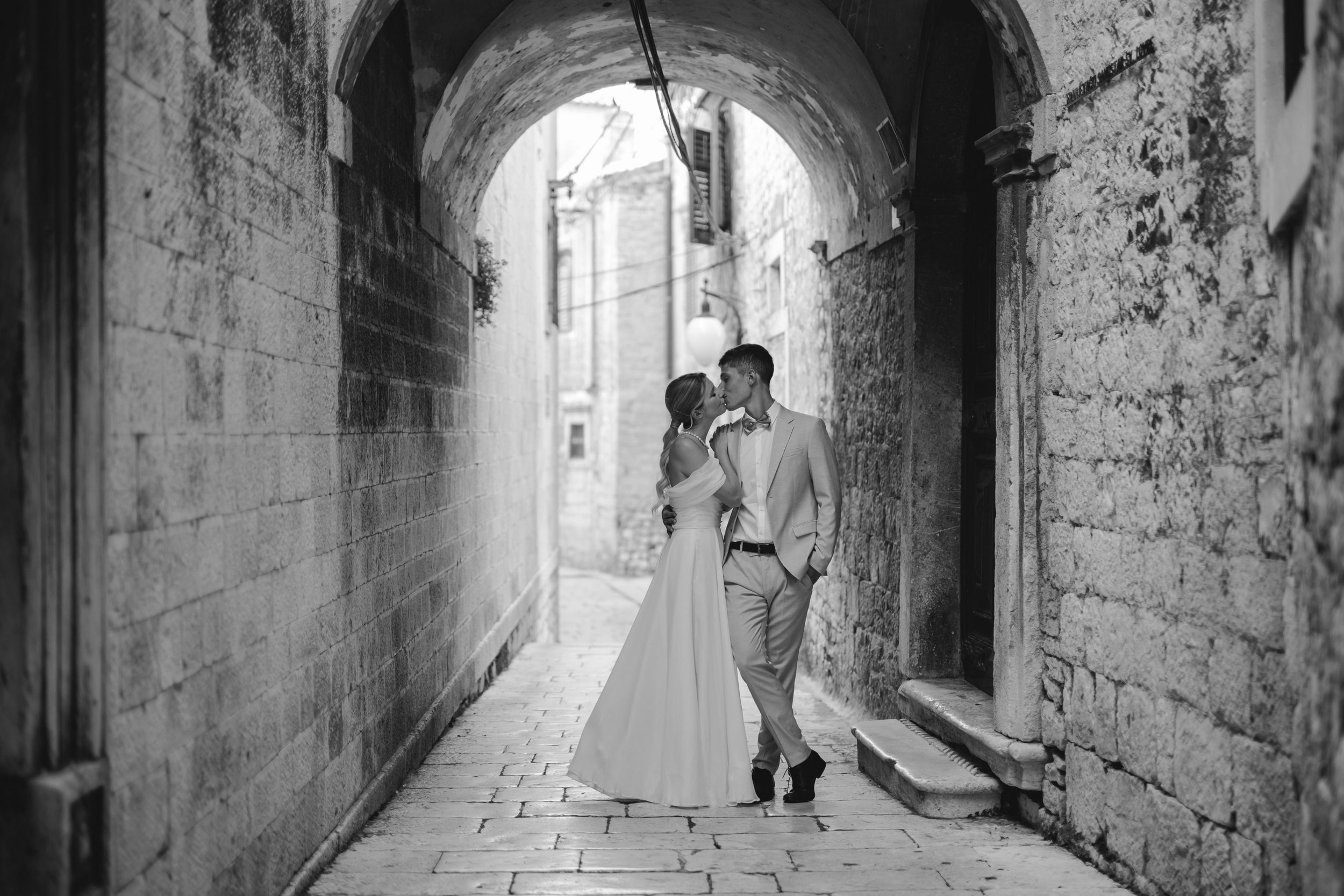Couple poses romantically in a stone archway passage during their wedding photoshoot.