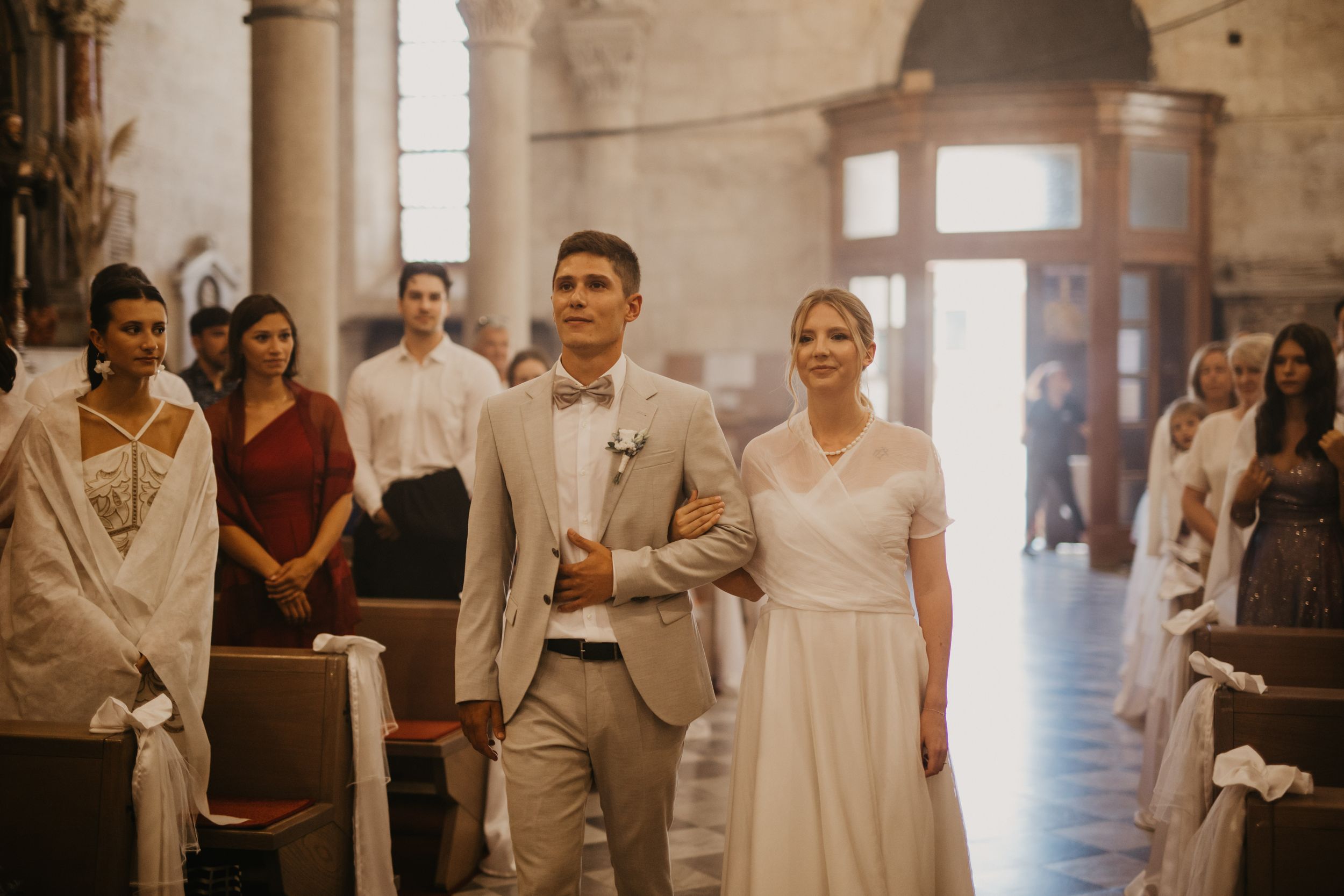 Wedding ceremony processional in historic church with elegant decor.