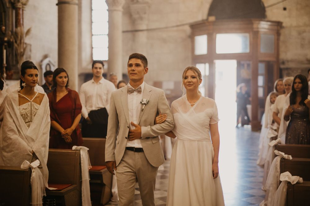 Wedding ceremony processional in historic church with elegant decor.