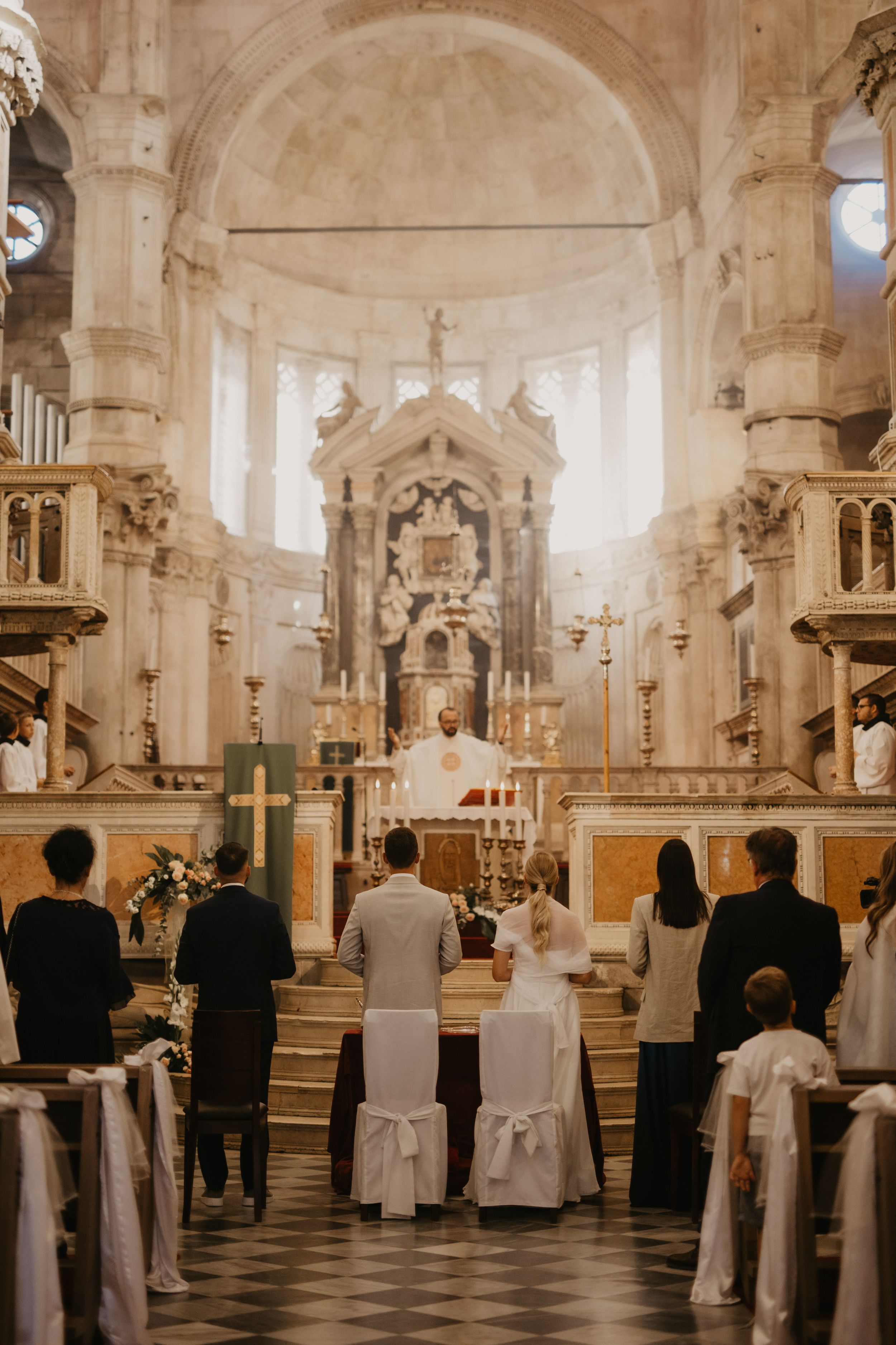 Traditional church wedding ceremony in ornate cathedral with checkered floor.
