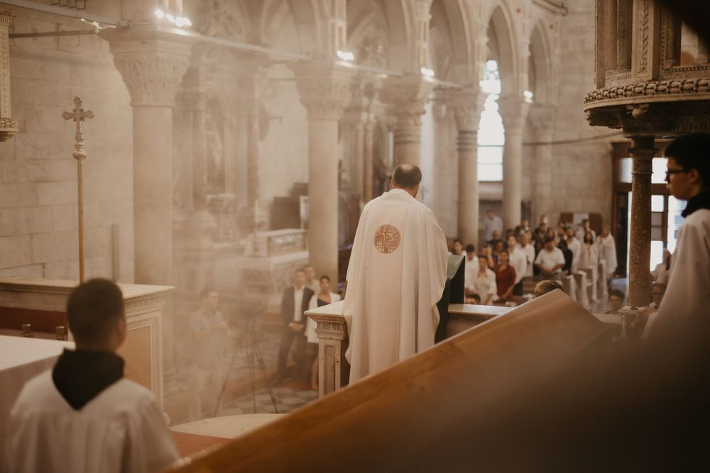 Catholic wedding mass with priest and altar servers in historic church interior.