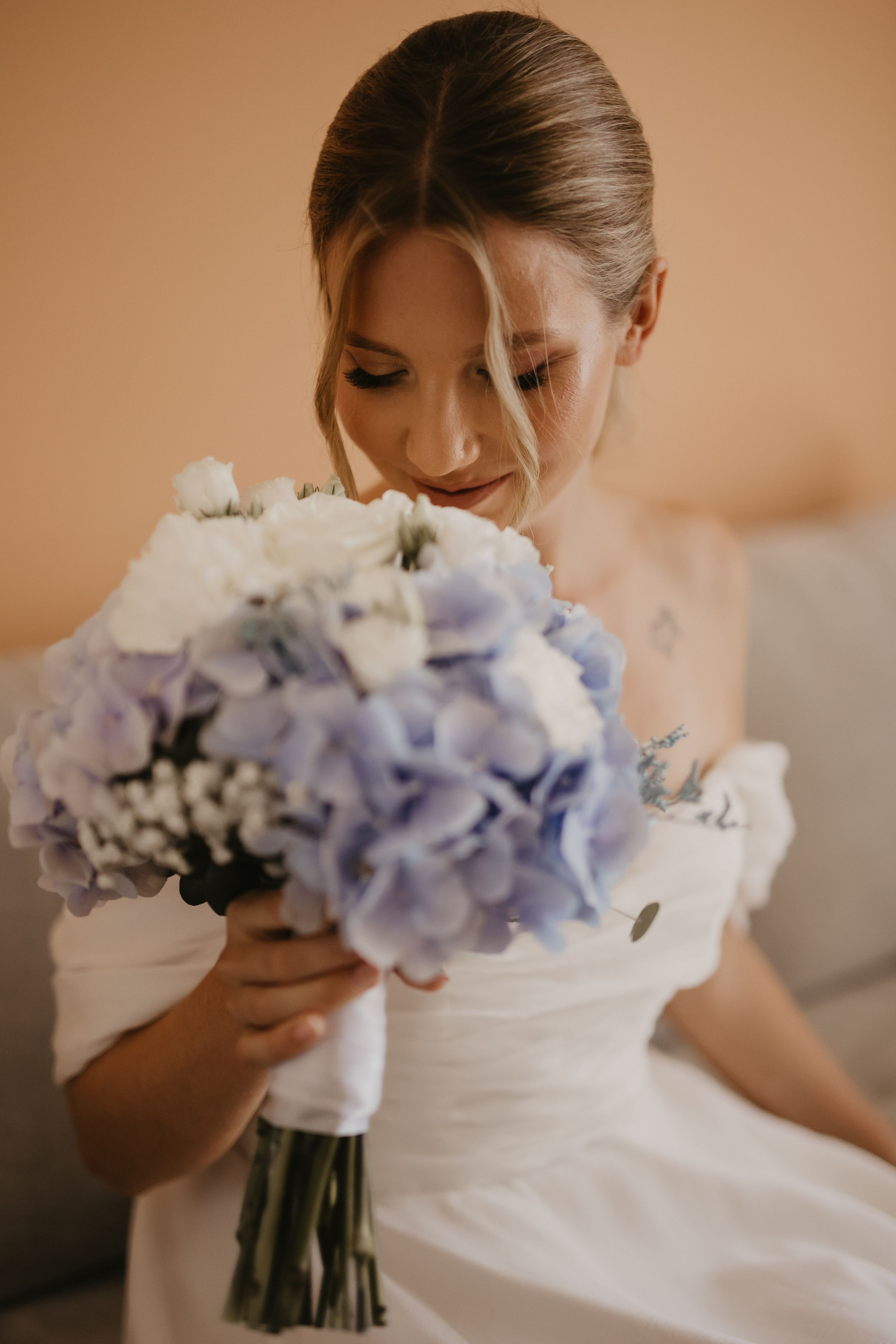 Bride in white dress holding beautiful blue and white hydrangea bouquet.