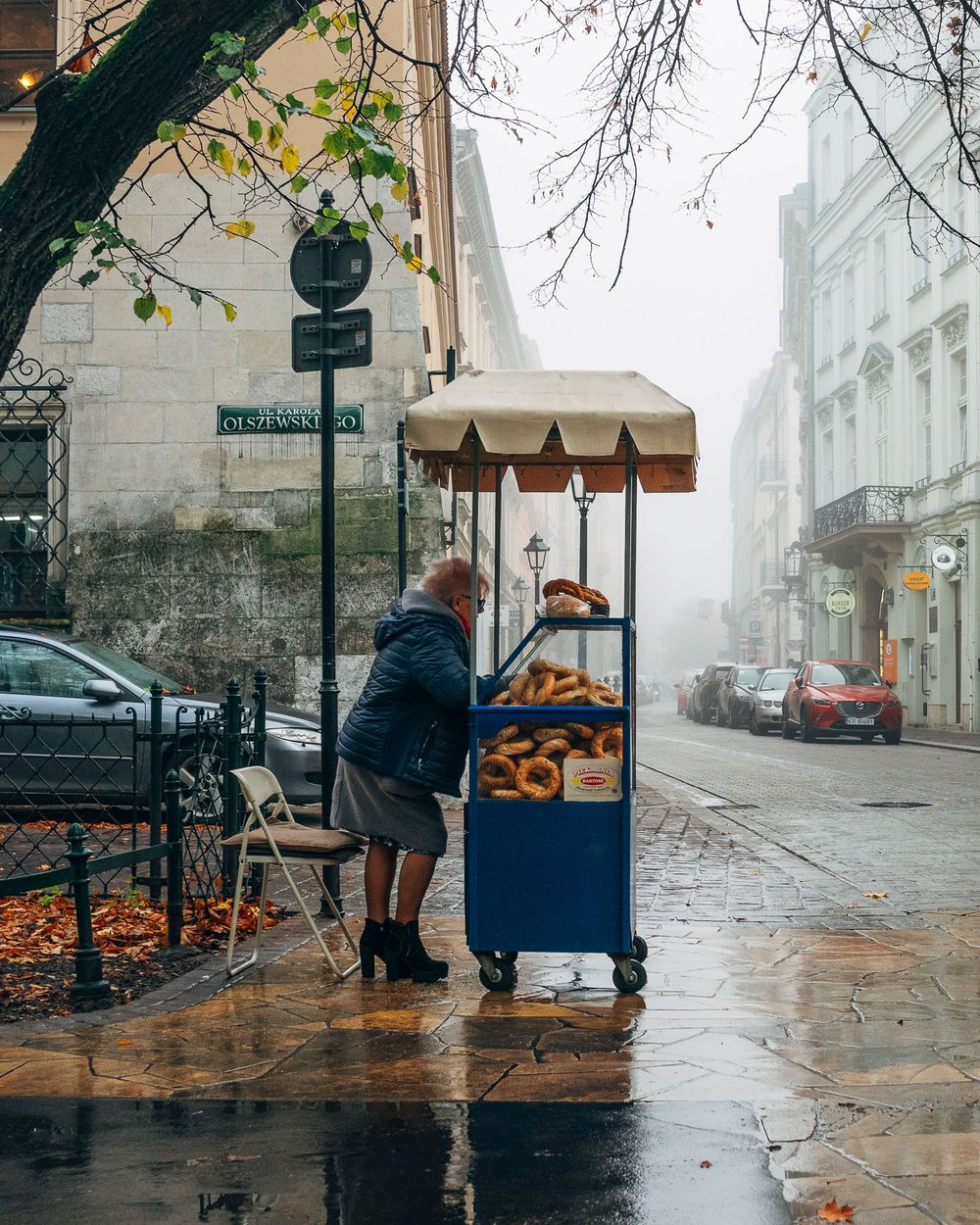 Foggy street scene with food vendor cart on rainy autumn day.