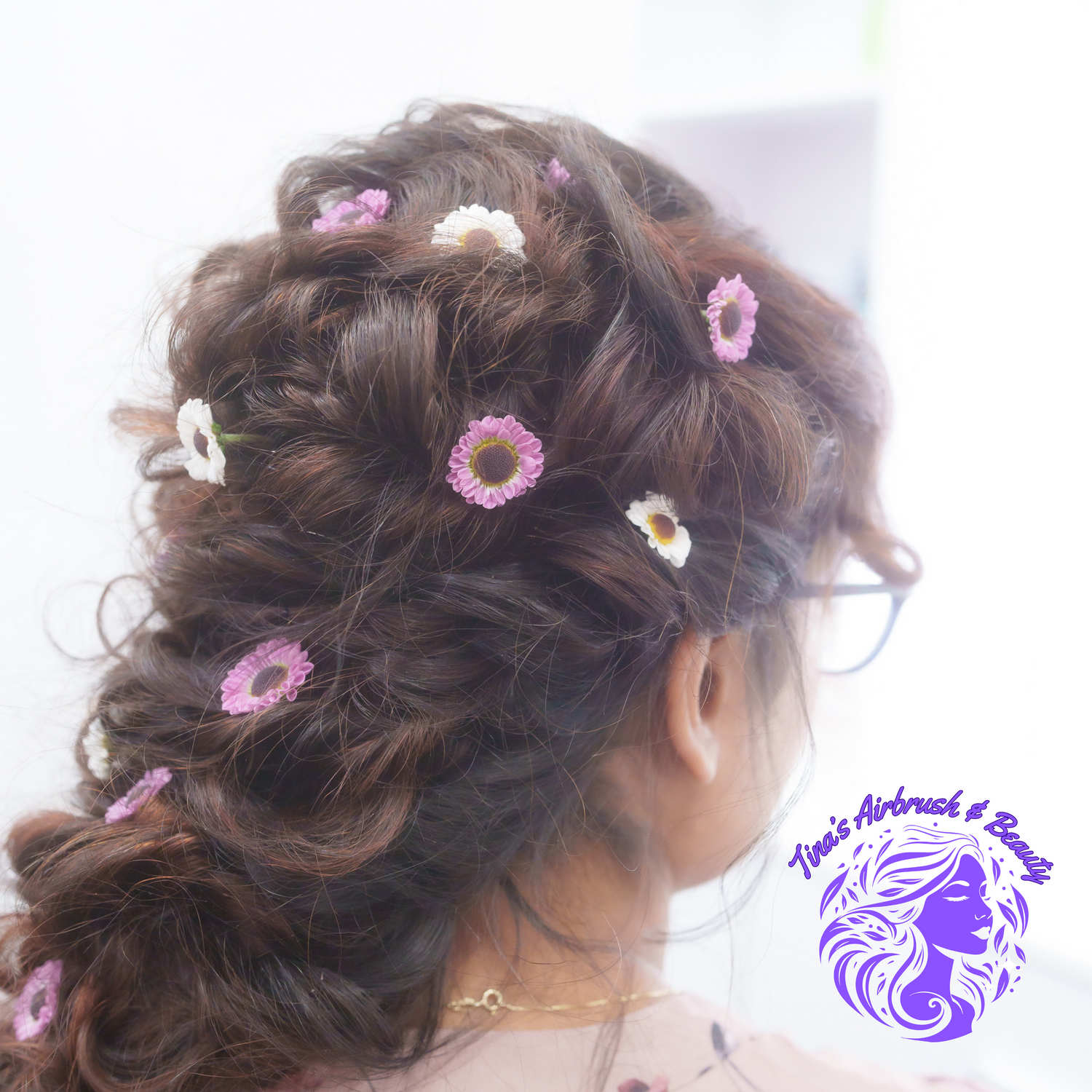 Elegant updo hairstyle decorated with small pink and white flowers.