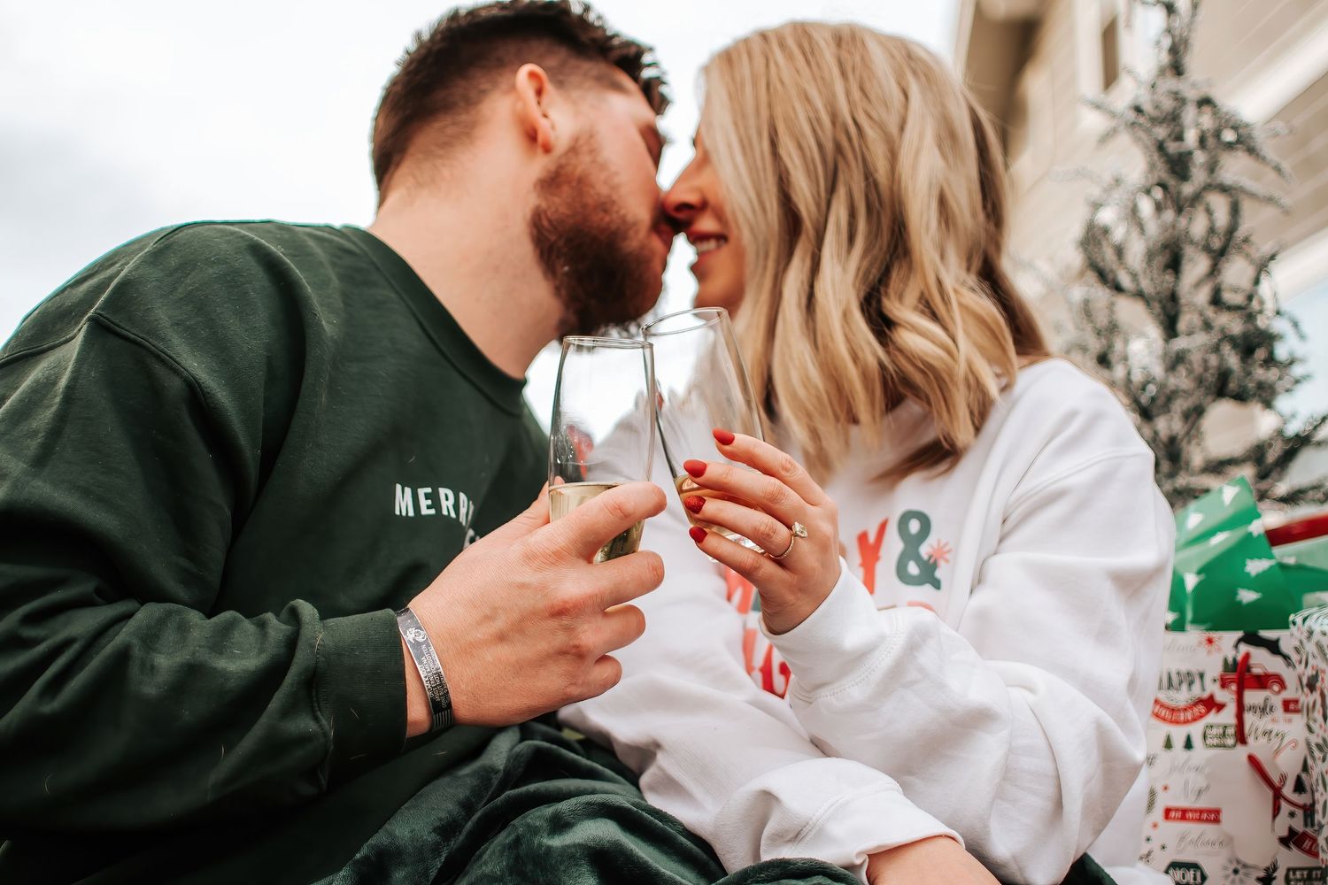 Couple in matching holiday sweaters sharing an intimate moment in front of a decorated Christmas tree in Prosser, Washington.