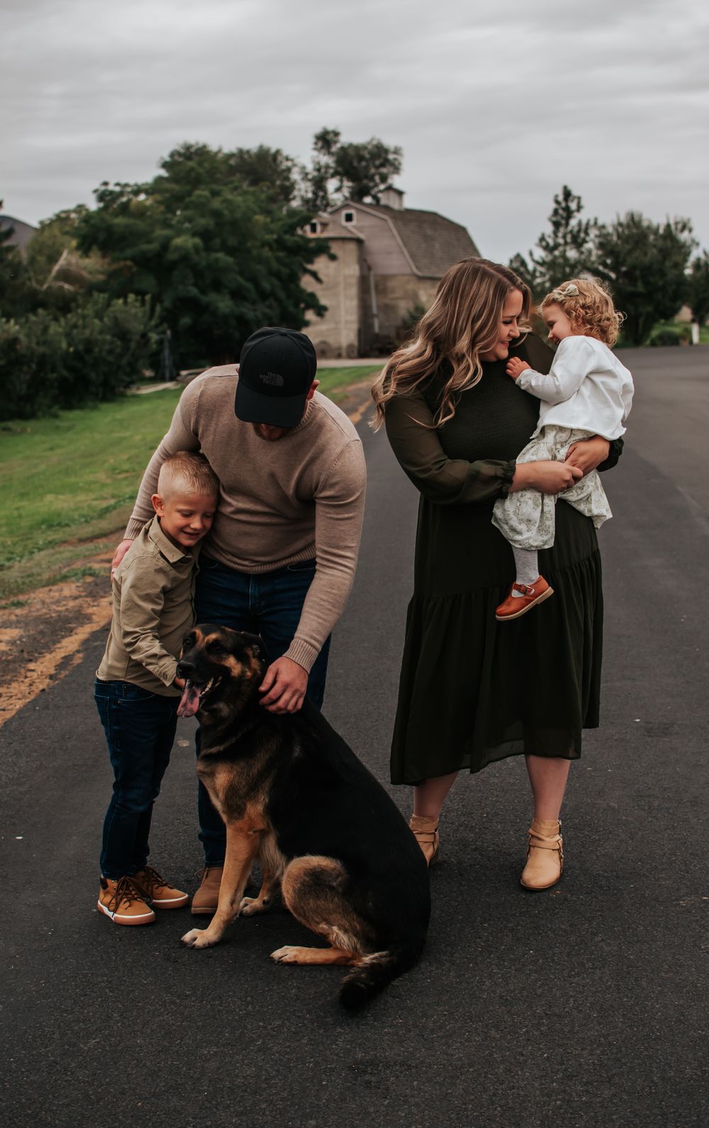 A family poses for a photo on a street with their German Shepherd dog in Tri Cities, Washington.