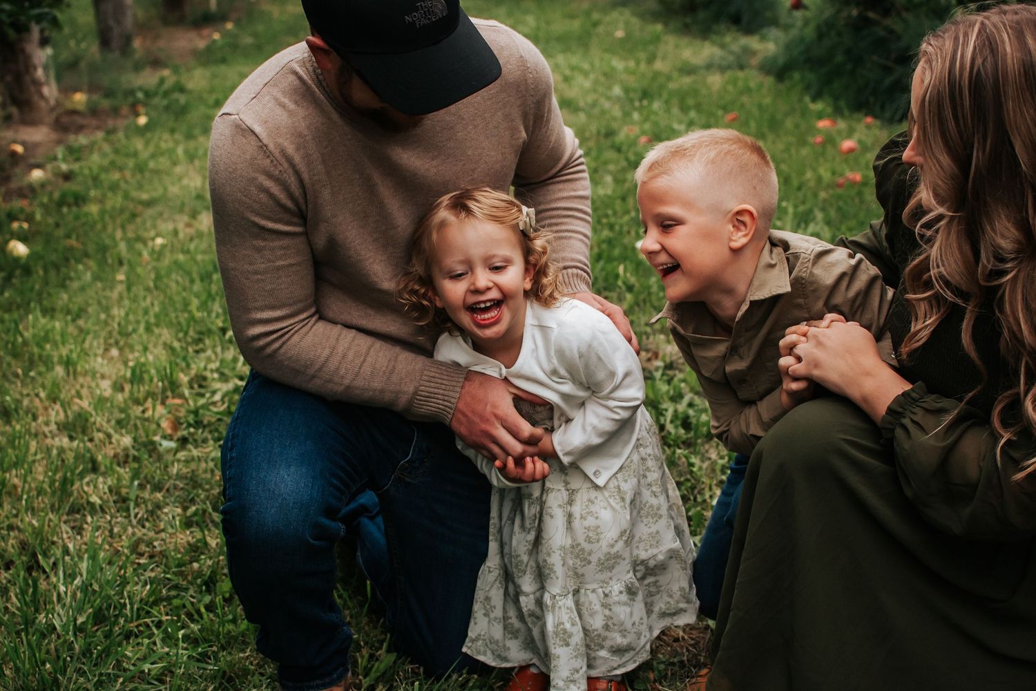 Family laughing and playing together outdoors on a sunny day in Tri Cities, Washington.