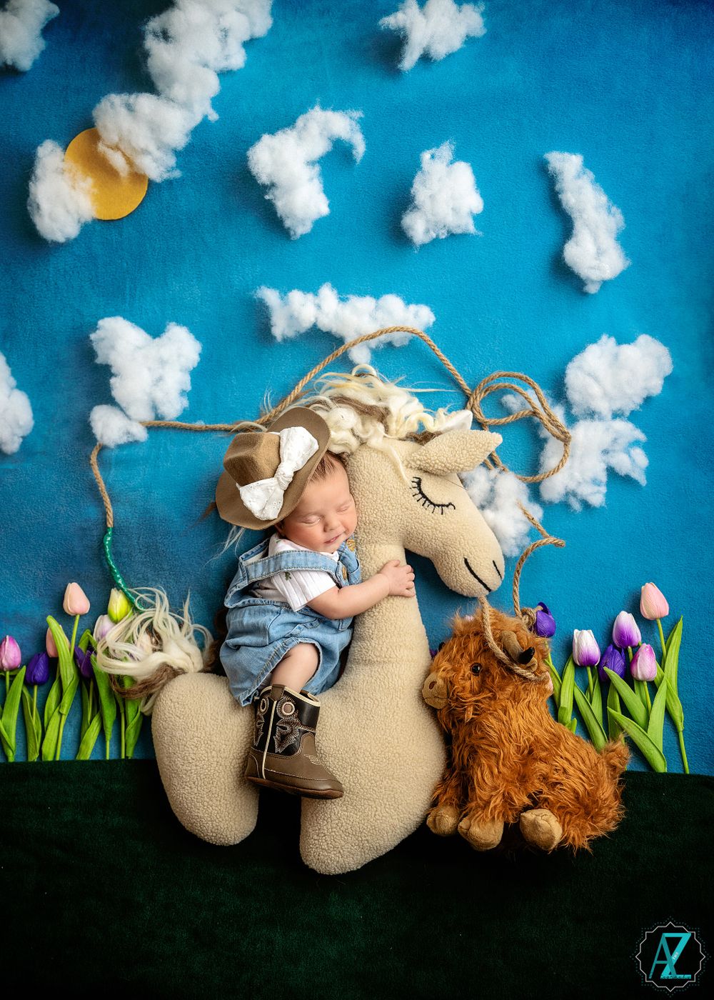 Whimsical nursery scene with stuffed unicorn, orange cat, and cotton cloud decorations against blue background.