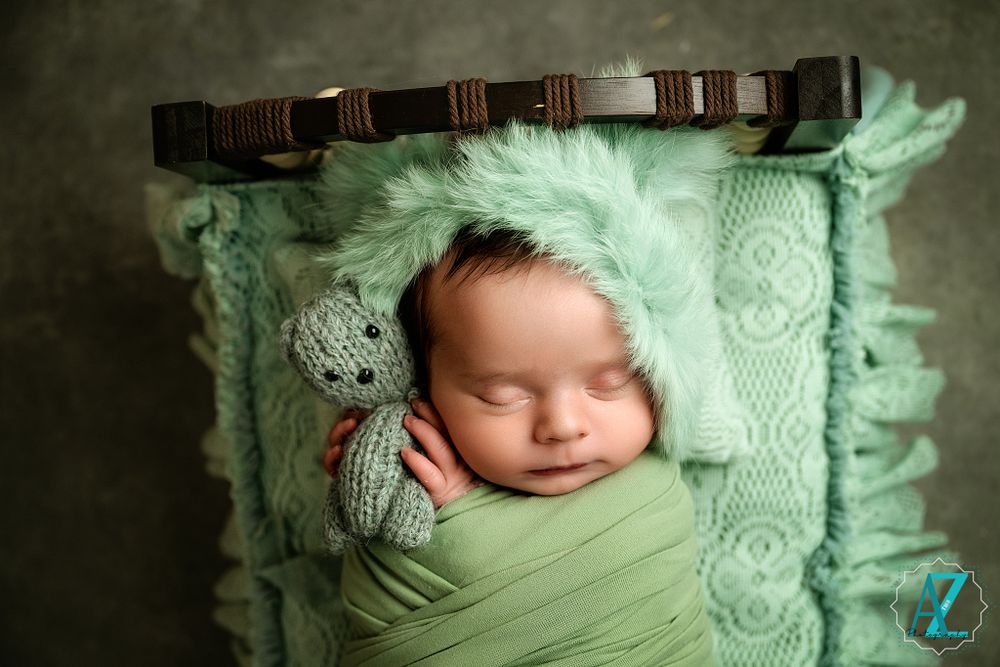 Artistic newborn photography with mint green wrap and vintage wooden accent.