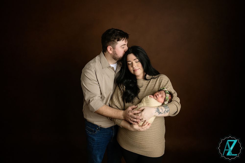 Intimate family portrait with neutral tones against dark backdrop.