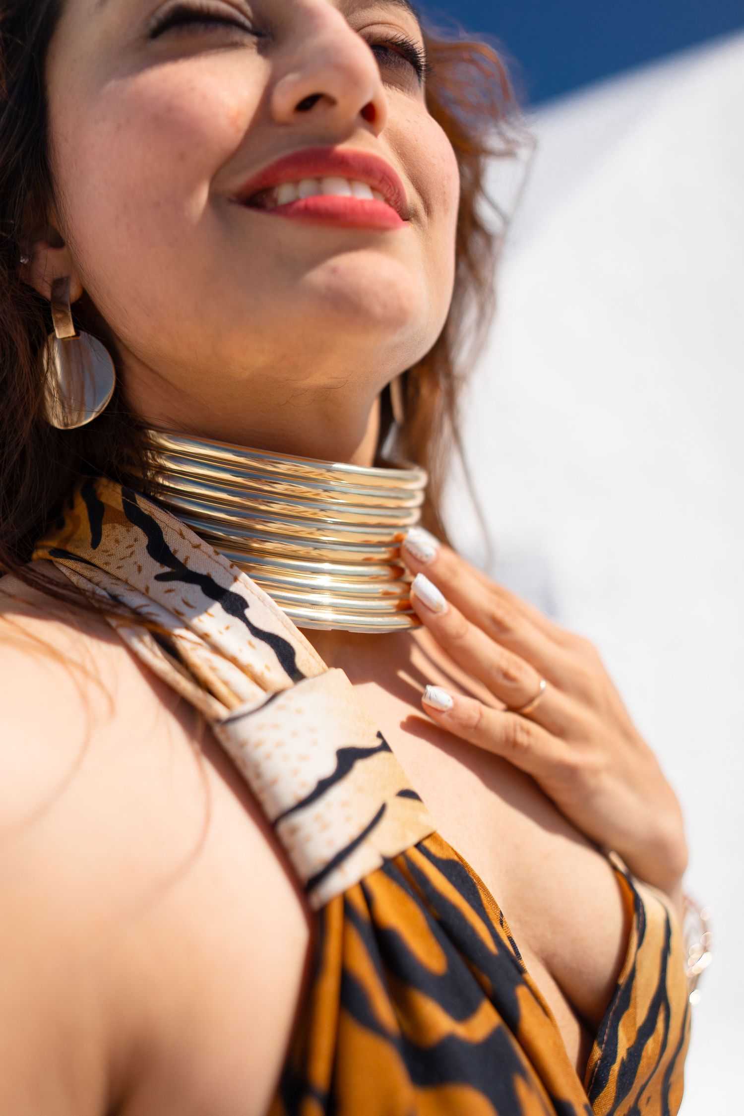Gold metallic choker necklace sparkles against sun-kissed skin in bright natural lighting.