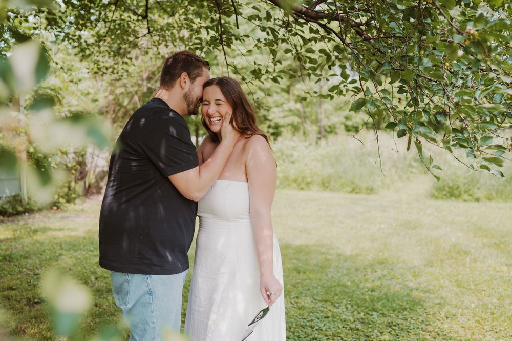 Couple sharing tender moment together in sunlit garden setting.