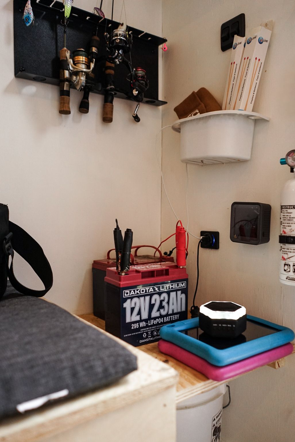 Fishing rod storage and battery setup in compact organization corner.