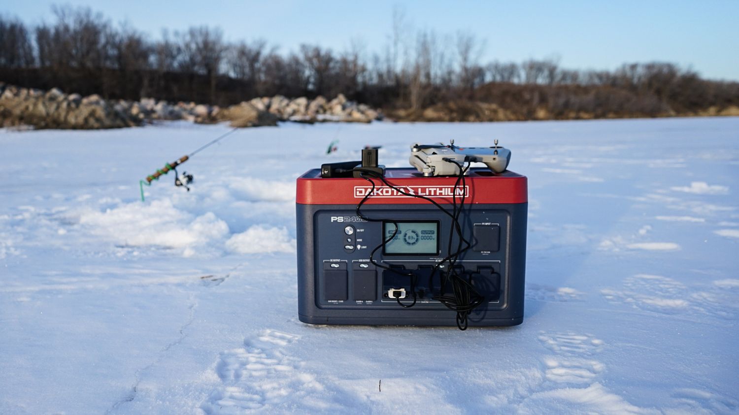 Portable Dakota Lithium power bank sitting on snowy ground with winter landscape in background.