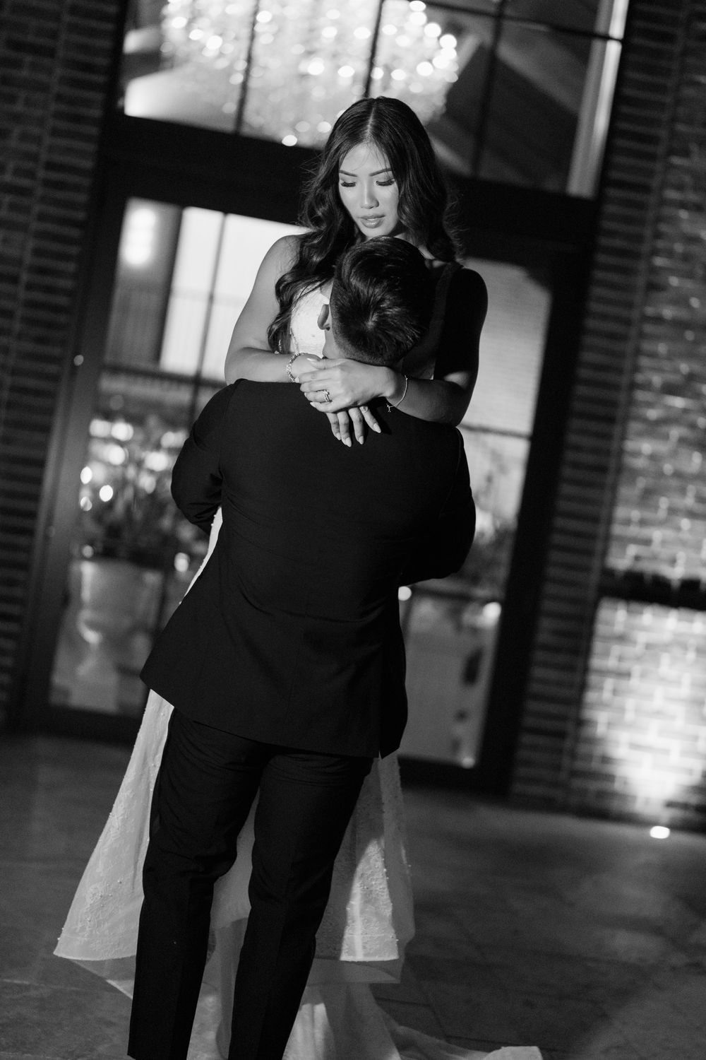 A black and white photo series showing a couple dancing together in an elegant indoor space with brick walls.