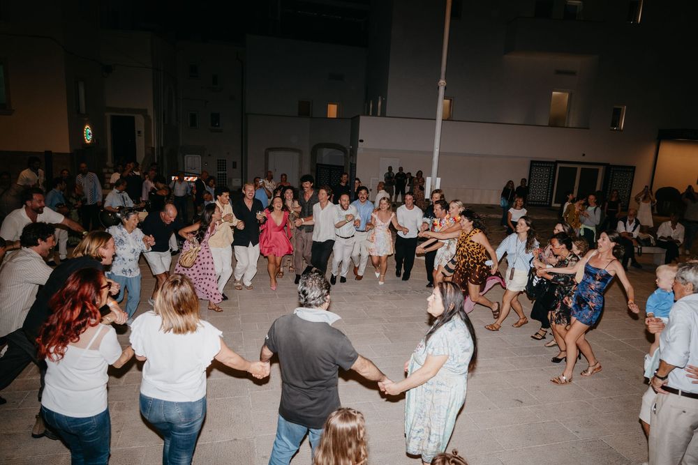 People dancing in a line formation at a social gathering in a large indoor venue.