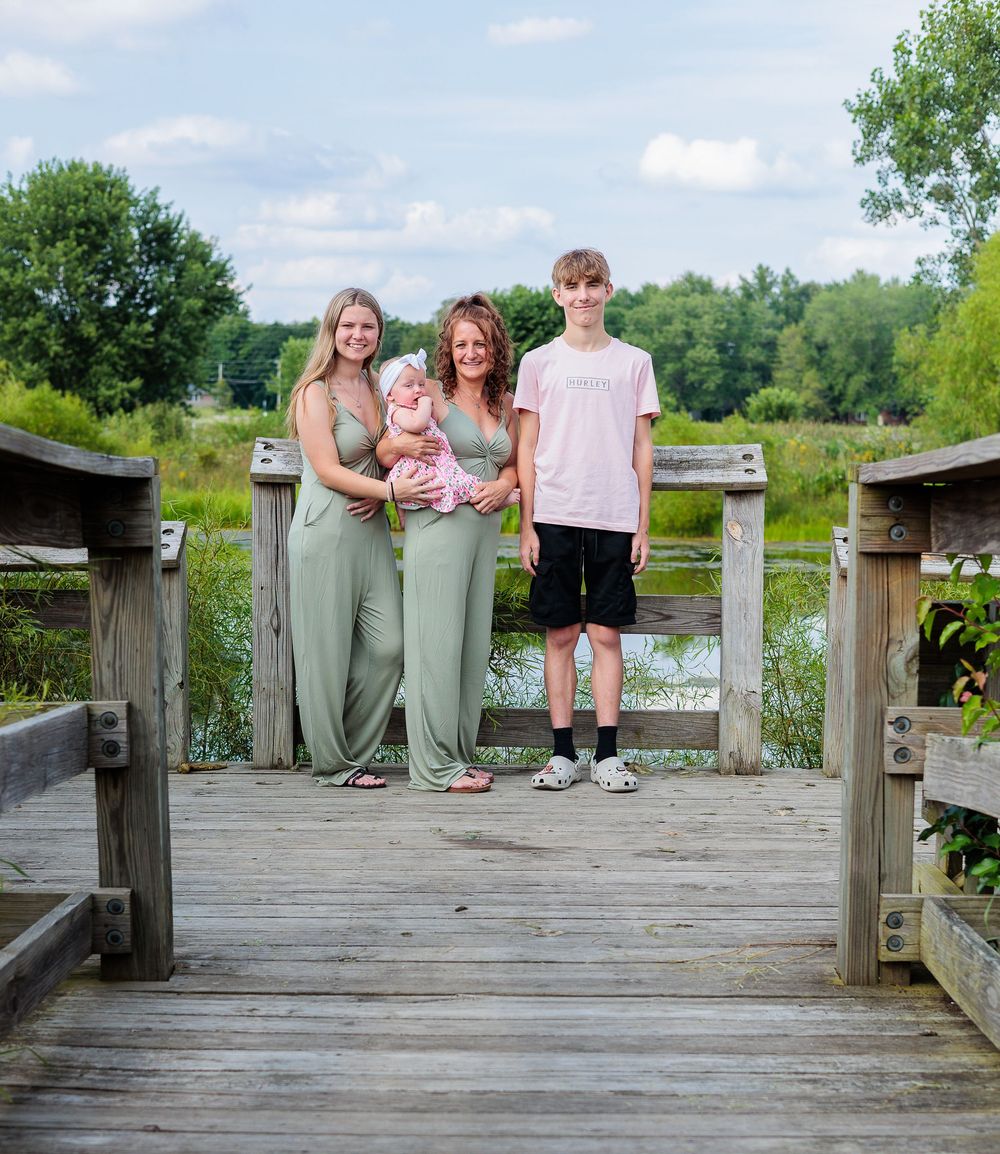 Family members gathered on a wooden dock overlooking a peaceful lake.
