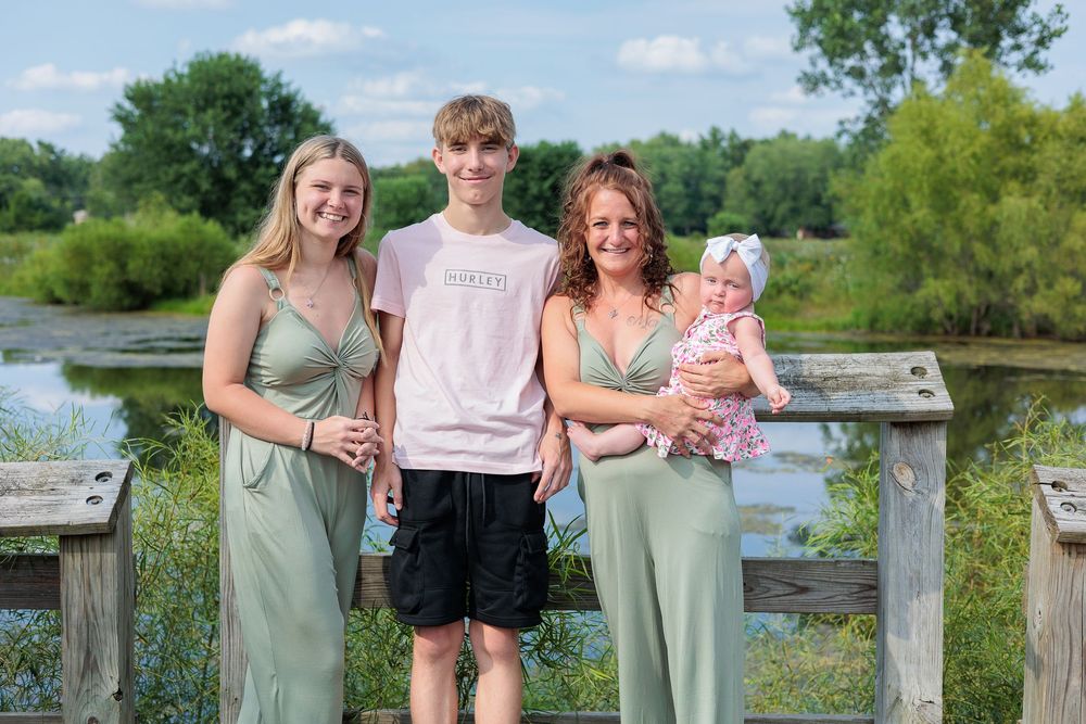 Family group standing together on a lakeside boardwalk during summer.