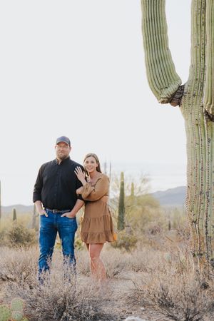 People walking through desert terrain with majestic saguaro cacti in the background.