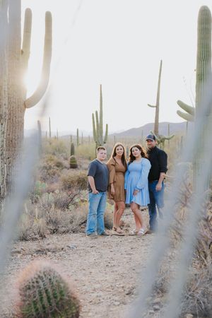 Group gathering in desert setting with towering saguaro cacti and mountain views.