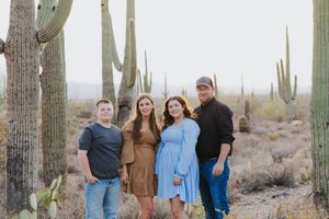 Desert photoshoot with multiple people positioned between majestic saguaro cacti.