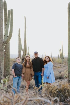 Desert landscape photography featuring group posed among towering saguaro cacti.