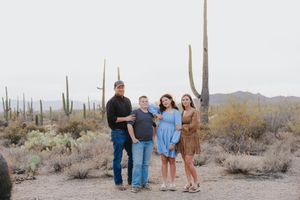 Desert gathering with people walking between massive saguaro cacti during sunset.