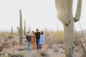 A family group stands together in a scenic desert setting with majestic saguaro cacti.