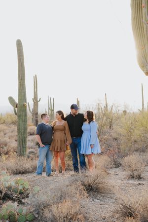 People enjoy a casual gathering in a desert landscape surrounded by saguaro cacti.