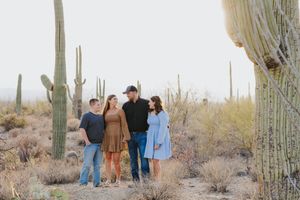 Desert photoshoot with several people positioned between towering saguaro cacti.