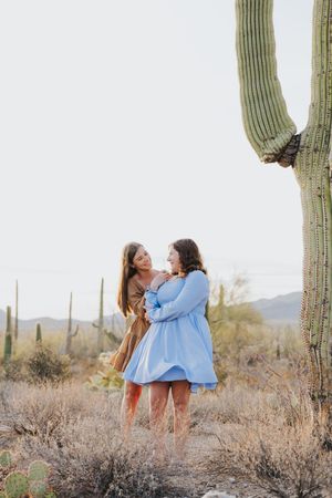 Friends sharing a joyful moment among saguaro cacti in the desert.