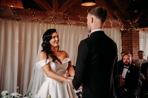 Two people in formal attire sharing a joyful moment during an indoor wedding ceremony.