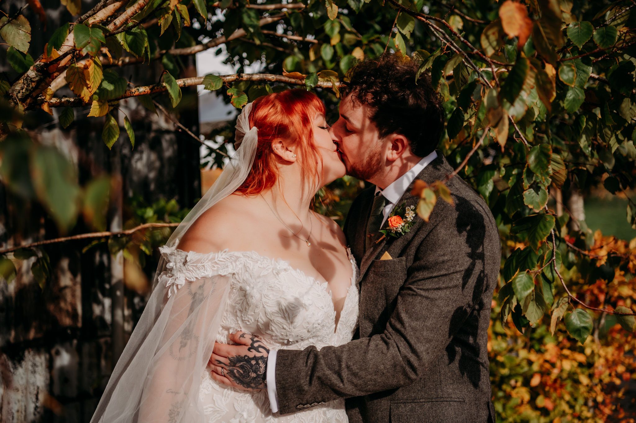 Autumn wedding scene with warm fall foliage and sunlight filtering through trees in the background.