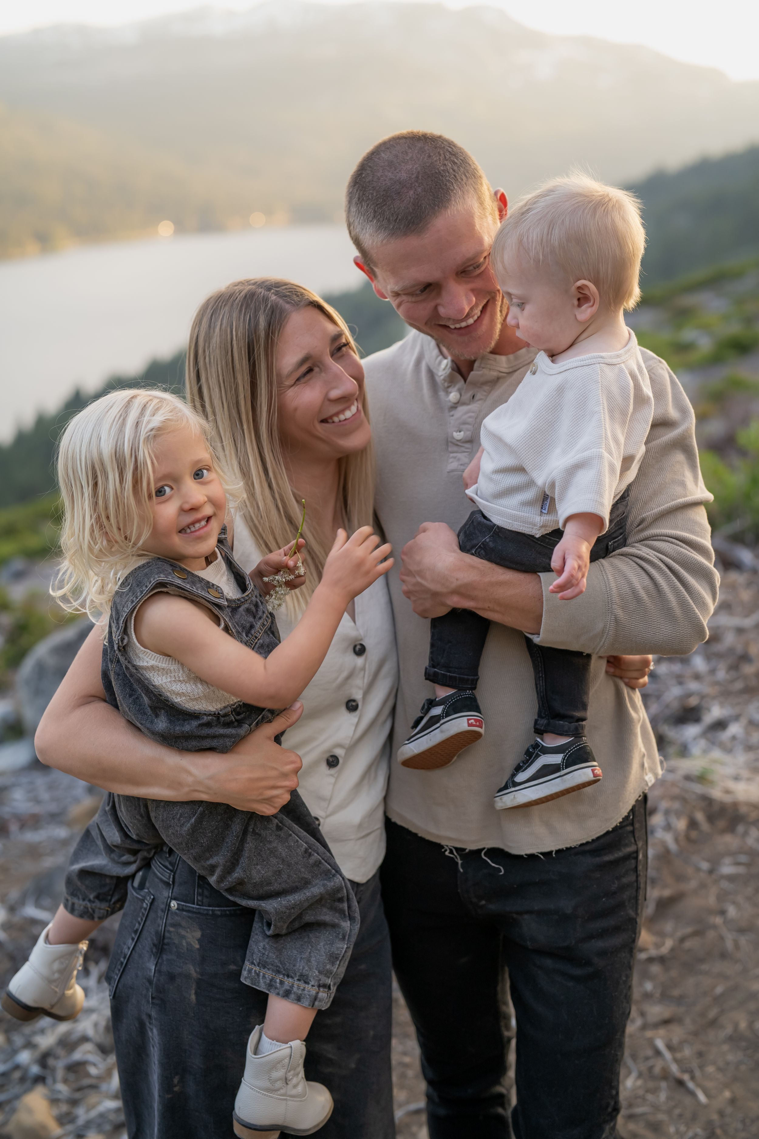 A family shares joyful moments together during a sunset photoshoot on a mountainside.
