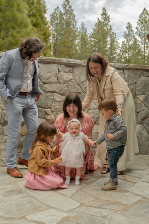 Family sitting together on stone patio while drawing with chalk in sequence of candid outdoor moments.