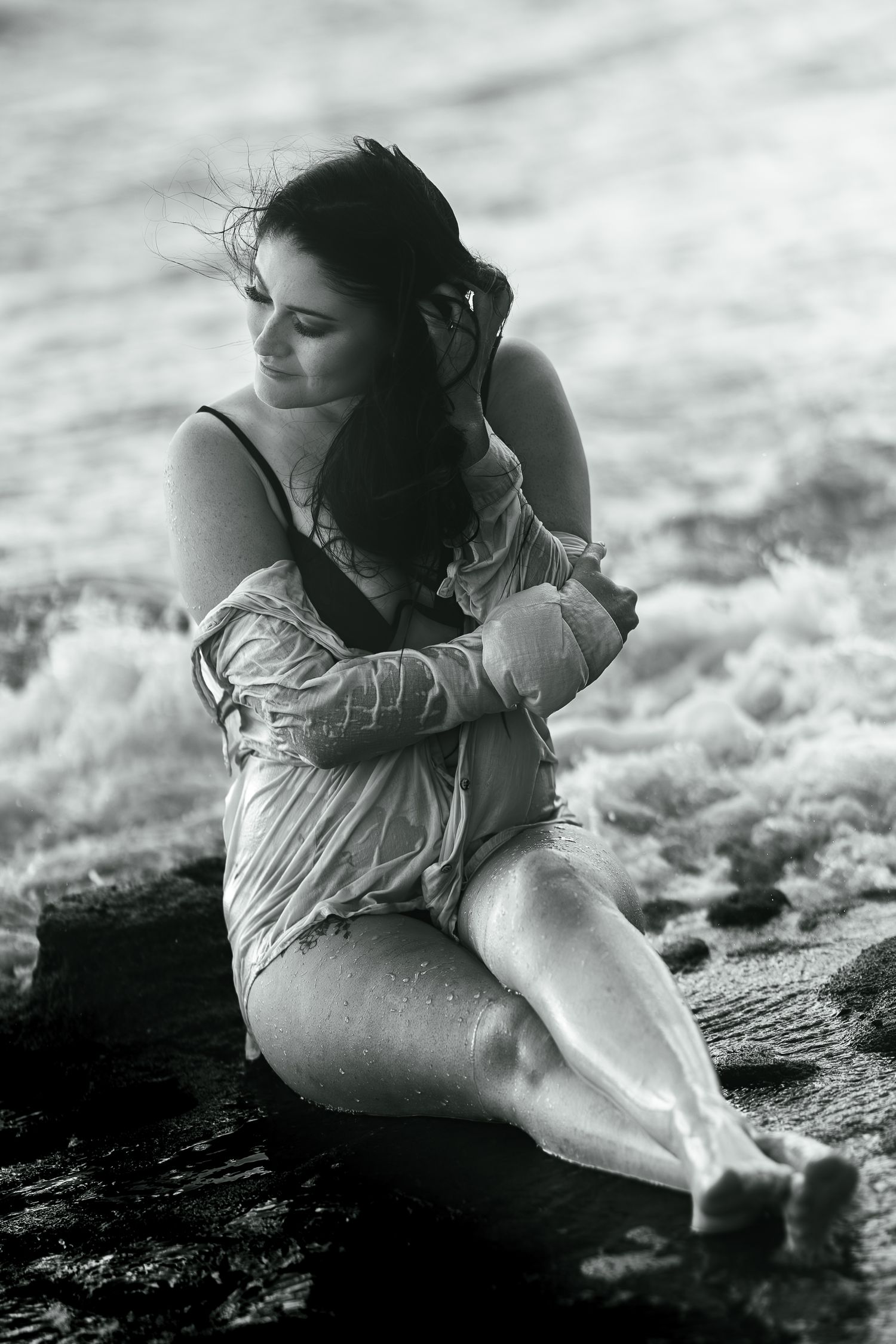 A black and white artful sequence showing a figure reclining on textured rocks near water.